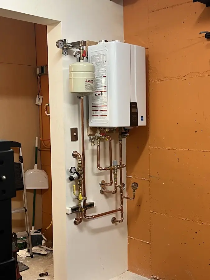 Plumbing technician inspecting water heater connections in St. Matthews